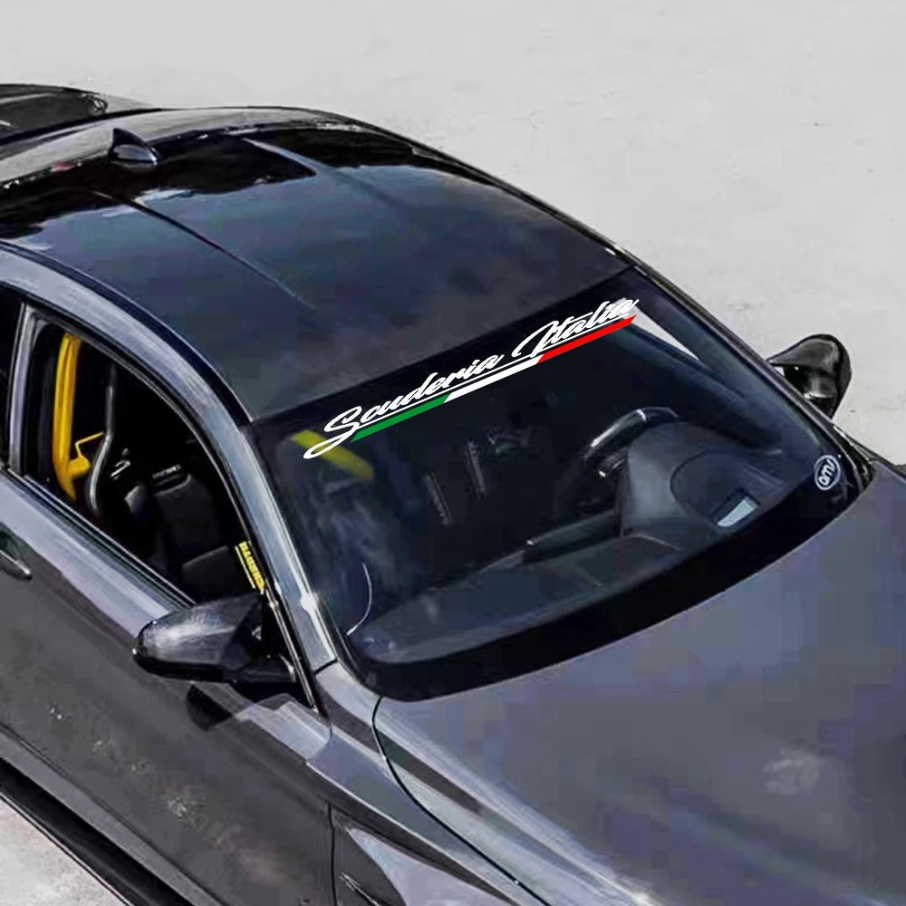 Car with Scuderia Italia decal on the windshield against a plain background