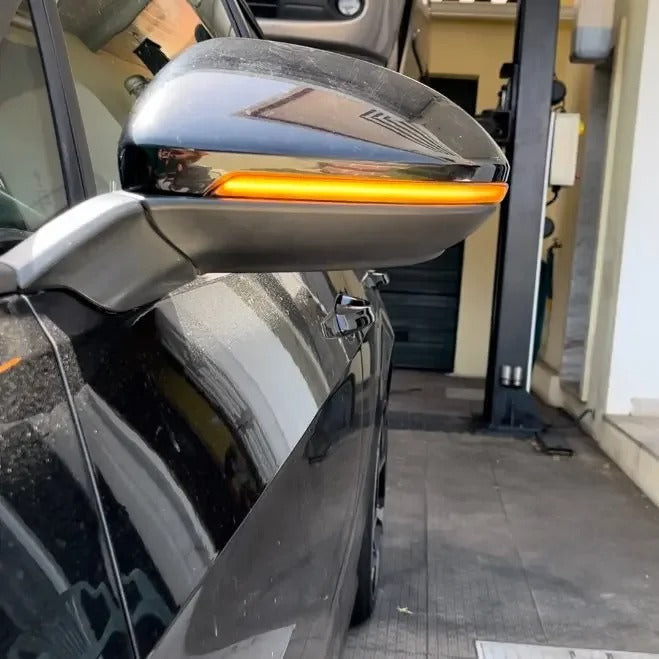 Car side mirror with turn signal light on, inside a garage.