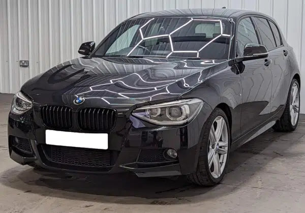 Black BMW car with a unique geometric design on the hood, parked indoors.